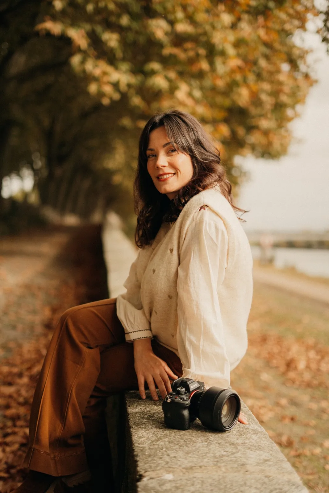 Pauline, photographe, posant en automne avec son boîtier le long de la Loire